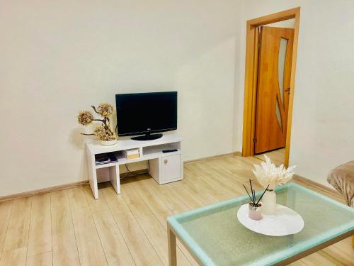 a living room with a tv and a table at Ezero apartamentai in Šiauliai