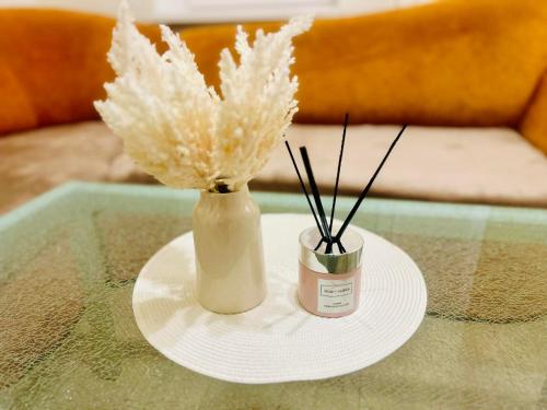 un jarrón blanco con algunas plantas secas en una mesa en Ezero apartamentai, en Šiauliai