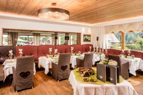 a restaurant with tables and chairs and a chandelier at Hotel Dorfer Alpine&Charming in Selva di Val Gardena