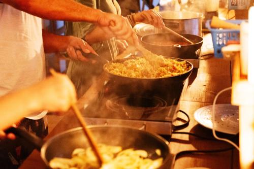 um grupo de pessoas cozinhando comida em panelas em um fogão em Aparra Surfcamp Capbreton em Capbreton