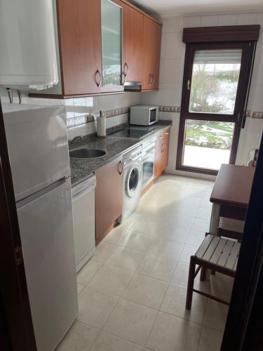 uma cozinha com um frigorífico branco e uma máquina de lavar louça em Apartamentos Fele2 em Felechosa