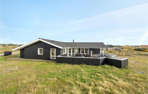 a black house on a grassy field at Holiday Home Bjerregårdsvej Hvide Sande Denm in Bjerregård