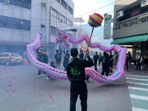 a man is holding a pole in a street with a kite at 佳林居 in Dahu