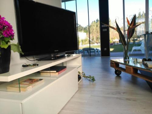 a living room with a large television on a white entertainment center at Casa Calima in Esteiro