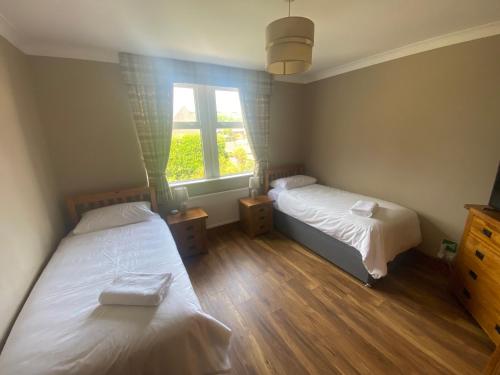 1 dormitorio con 2 camas y ventana en Houghton Park Holiday Cottage en Newcastleton