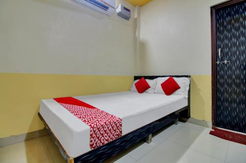 a bedroom with a bed with red pillows on it at Hotel O Vinit Lodging in Nagpur