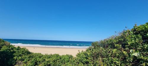 a beach with people on the sand and the ocean at Complexo Baleia Azul Camping in Ponta do Ouro