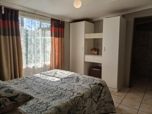 a bedroom with a bed and a window at Villa Luca Guesthouse & Chalets in Swartruggens