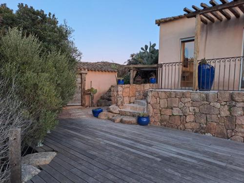 a house with a stone wall and a wooden deck at Mer & Maquis in Bonifacio