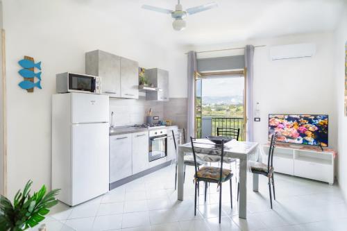 una cucina con elettrodomestici bianchi e tavolo con sedie di !!! 2 MIN DALLA SPIAGGIA !!! - Casa Vacanze Coralli a Sciacca