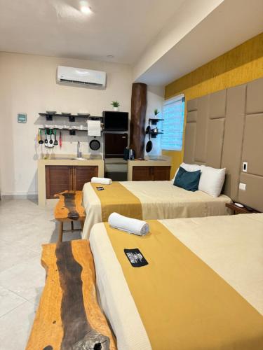 a room with three beds and a kitchen with a counter at Suites Valentina in Puerto Morelos