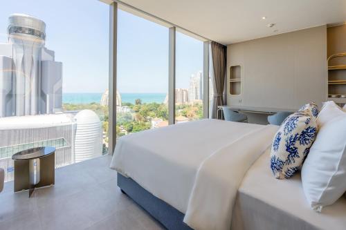 a bedroom with a large bed and a large window at Akara Hotel Pattaya in Pattaya North