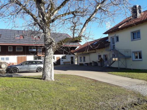 ein Auto, das vor einem Haus mit einem Baum parkt in der Unterkunft Haus Sprißler in Markdorf