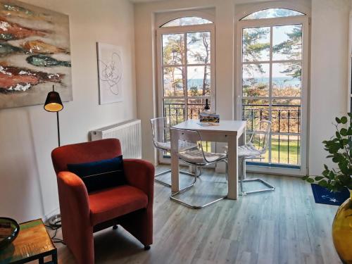 a living room with a table and a chair and windows at Haus Meeresblick - Ferienwohnung Nordstern A 1.16 (Ref. 138647) in Baabe