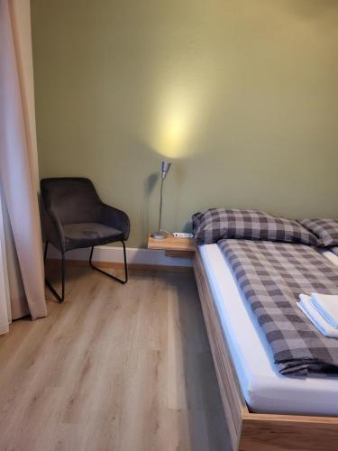 a small bedroom with a bed and a chair at Interlaken Apartments in Interlaken