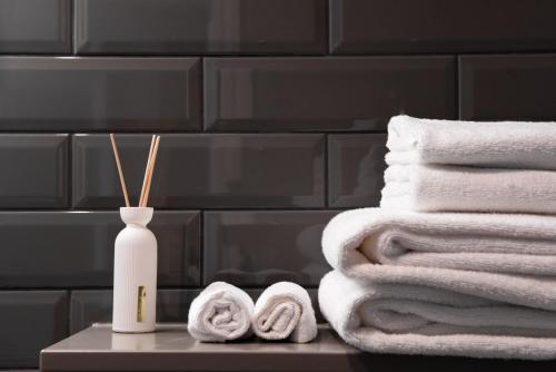 a bathroom with white towels and a bottle of cleaner at Aparthotel Amella in Rīga