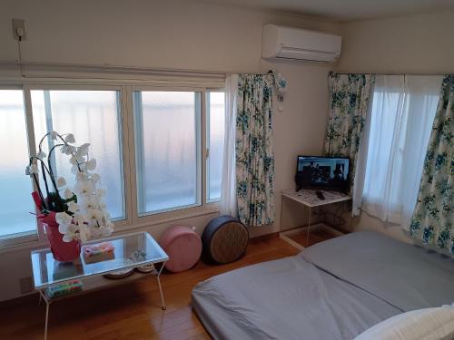 1 dormitorio con 1 cama, TV y ventanas en Tokyo downtown牡丹莊, en Tokio