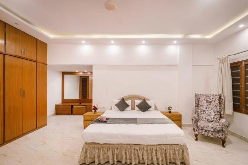 a bedroom with a large bed and a chair at Woodstone Manor by JadeCaps Penthouse Indiranagar in Bangalore