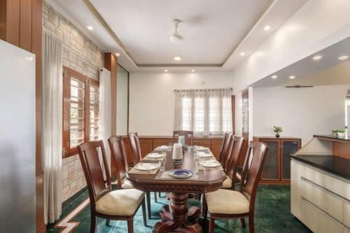 a dining room with a wooden table and chairs at Woodstone Manor by JadeCaps Penthouse Indiranagar in Bangalore