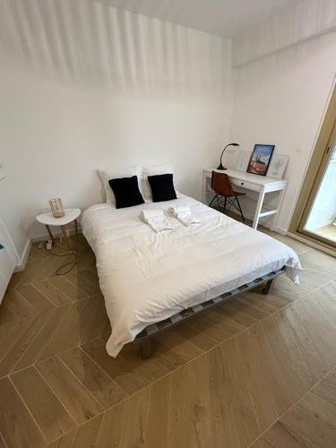 une chambre blanche avec un grand lit et un bureau dans l'établissement Studio L'échappée avec lit double et parking sous-sol privatif, à Chartres