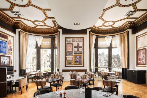 un restaurante con mesas, sillas y ventanas en Hotel Indigo - Edinburgh - Princes Street, an IHG Hotel, en Edimburgo