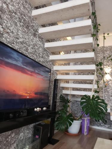 a staircase in a living room with a large screen tv at 2 bedroom duplex Durrës in Durrës