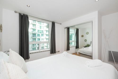 - une chambre avec un grand lit blanc et un grand miroir dans l'établissement Compact 2 Bed Good Transport Links, à Londres