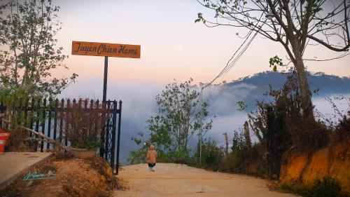 a person walking down a dirt road with a sign at Tuyên Chiến Home - Nhà Gỗ in Ấp An Kroët
