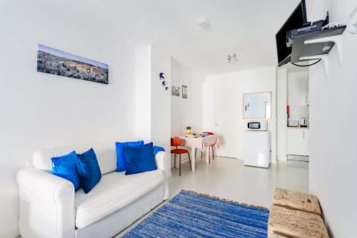 a white living room with a white couch and blue pillows at Alfama Studios in Lisbon