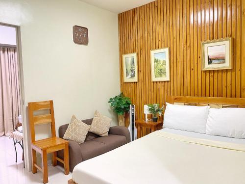 a bedroom with a bed and a chair and a couch at Cool Breeze Brenthill Deluxe in Baguio