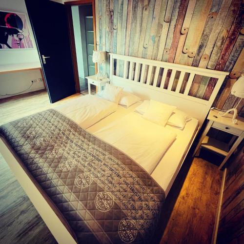a large bed in a bedroom with a wooden wall at Zum Rayers Café-Restaurant & Boutique-Hotel in Oberrotweil