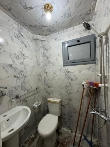 a bathroom with a toilet and a sink and a tv at شقه غرفتين جديده وعفش جديد وفرش جديد in Mansoura