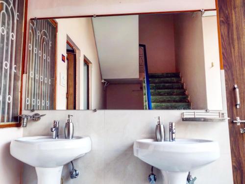 two white sinks in a bathroom with a mirror at Live Free Hostel Varanasi in Varanasi
