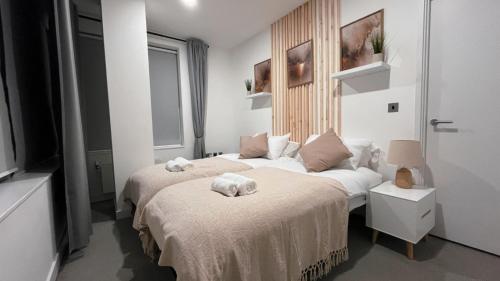 a bedroom with two beds with towels on them at Luxury Ascot Apartment with Parking in Bracknell