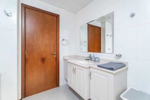 a bathroom with a sink and a wooden door at Nasma Luxury Stays - Exquisite 4BR Villa, with a Private Pool in Ras al Khaimah