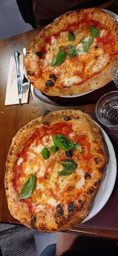 two pizzas sitting on plates on a table at Partenope 10 in Naples
