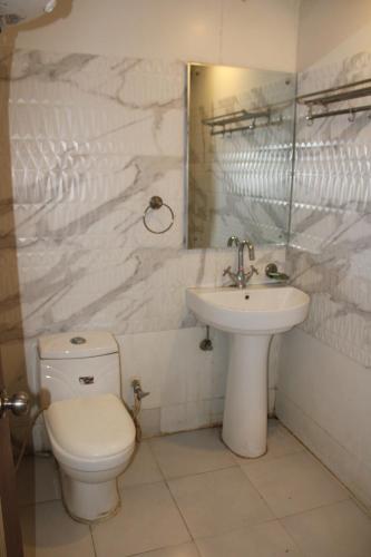 ZirakpurにあるHOTEL FIRSTの白いバスルーム(トイレ、シンク付)