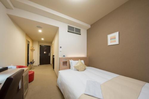 a bedroom with a large white bed in a room at Shizutetsu Hotel Prezio Numazu in Numazu