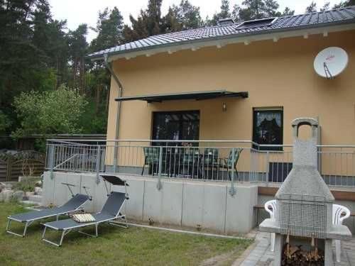 a house with two lawn chairs and a balcony at Doppelferienhaus am See & Wald in Krakow am See