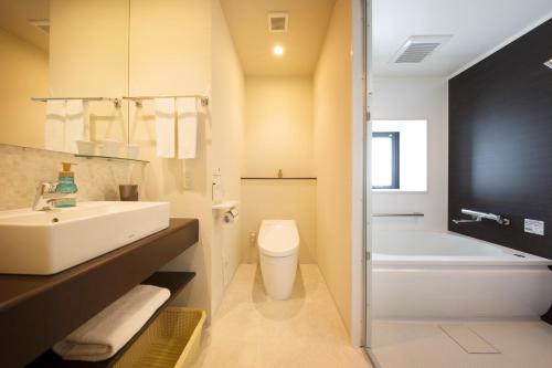 a bathroom with a sink and a toilet and a tub at Shizutetsu Hotel Prezio Numazu in Numazu