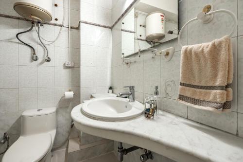 a bathroom with a sink and a toilet and a mirror at The Atlantis Duplex by JadeCaps 3BH Off MG road in Bangalore