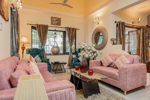 a living room with pink couches and a table at The Atlantis Duplex by JadeCaps 3BH Off MG road in Bangalore