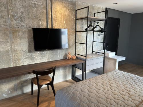 a bedroom with a bed and a desk with a television at Nord One in João Pessoa