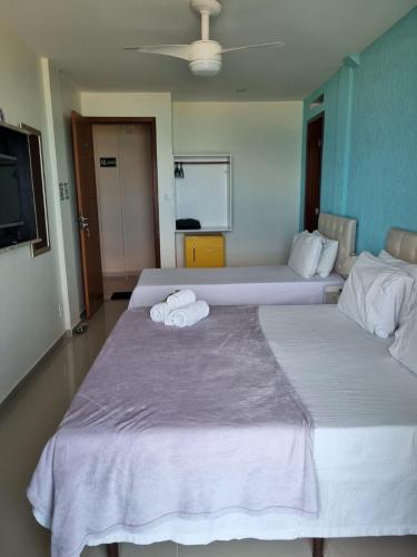 two beds in a hotel room with towels on them at Hotel Aconchego Da Vila in Saquarema