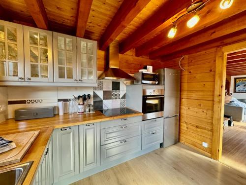 a kitchen with white cabinets and wooden ceilings at Charming, cosy chalet nestled in a breathtaking surrounding with spectacular, stunning mountain views in La Chapelle-dʼAbondance