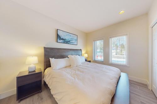 a bedroom with a large bed with a nightstand and two windows at Deschutes Delight in Bend