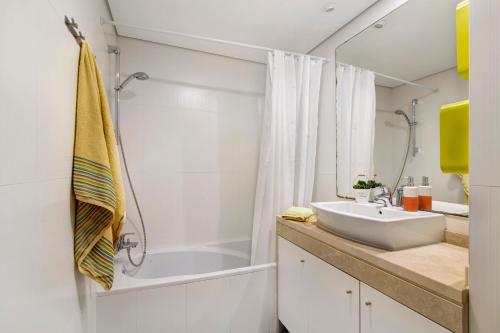 a bathroom with a sink and a tub and a shower at Apartamento Rossio in Albufeira