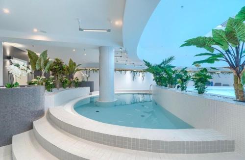 a large swimming pool in a building with palm trees at Apartments White Sky 26 Hanza Tower POOL JACUZZI SAUNA in Szczecin