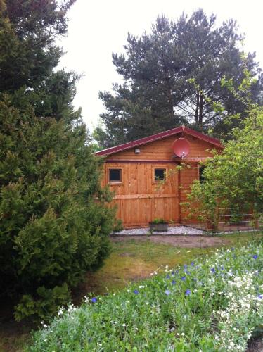 a wooden cabin with a fence and trees and flowers at Ferienbungalow Nautik in Hoppenwalde