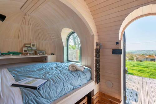 Cama en habitación pequeña con ventana abovedada en Prosecco - Lydcott Glamping Cornwall, sea views en East Looe